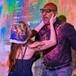 Two people playfully covered in colorful powder, sharing a joyful moment.