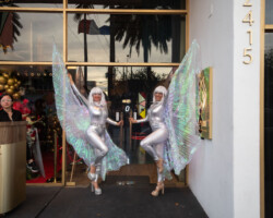Hora Loca Entertainment recibiendo a los invitados. Two performers in silver costumes pose mid-air in front of a shop window.