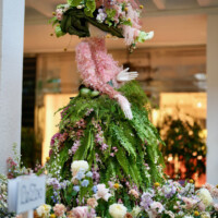 A floral mannequin decorated with pink and green flowers stands among blooms.