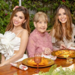 Three generations of women enjoying a meal together outdoors.