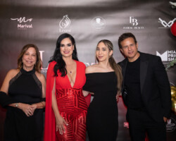 Four people posing at a formal event with a branded backdrop.