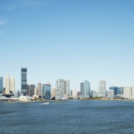 City skyline with modern buildings by the waterfront under a clear blue sky.