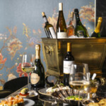Elegant wine and champagne display with appetizers and floral backdrop.
