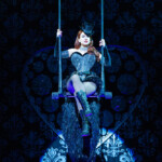 A performer in a dark corset and stockings on a swing with dramatic lighting.