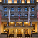 https://www.accorhotels.com/A568 Elegant theater entrance illuminated at dusk with American flags.