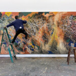 Artist creating vibrant graffiti art on a large wall using spray paint.