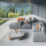 Modern gray sectional sofa with orange accents in a stylish living room overlooking a scenic view.