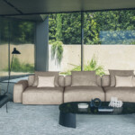 Modern living room with beige sectional sofa and glass coffee table.