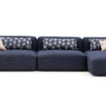 Modern dark blue sectional sofa with beige accent pillows.