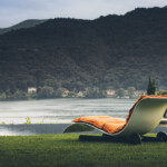 Modern lounge chair facing a serene lake and misty mountains.