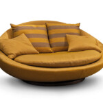 Round mustard-yellow couch with striped and solid cushions.