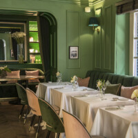 Elegant dining area with green walls and white tablecloths.