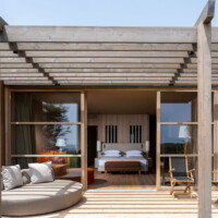 Modern outdoor patio with wooden deck and cozy seating facing a bedroom.