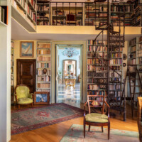 Elegant vintage library room with tall bookshelves and wooden spiral staircase.