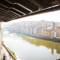 View of a calm river with historic buildings along its banks under a wooden roof.