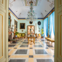 Elegant historic room with chandelier and classical decor.