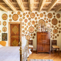 Rustic bedroom with wooden ceiling and decorative plates on the wall.