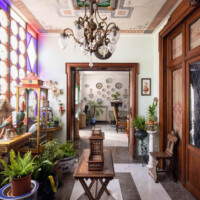Elegant vintage room with antique furniture and lush plants.