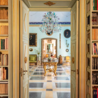 Elegant room viewed through a doorway, featuring a chandelier and classic furniture.