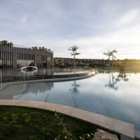 Modern building reflected in a calm pool at sunset.