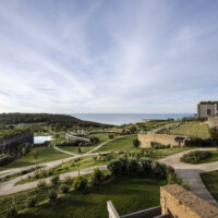 Scenic view of a historic fortress with lush greenery and winding paths under a cloudy sky.