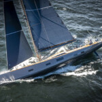 A sleek sailboat with blue sails gliding through the water.