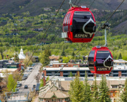 Red cable cars ascend over a scenic mountain village.
