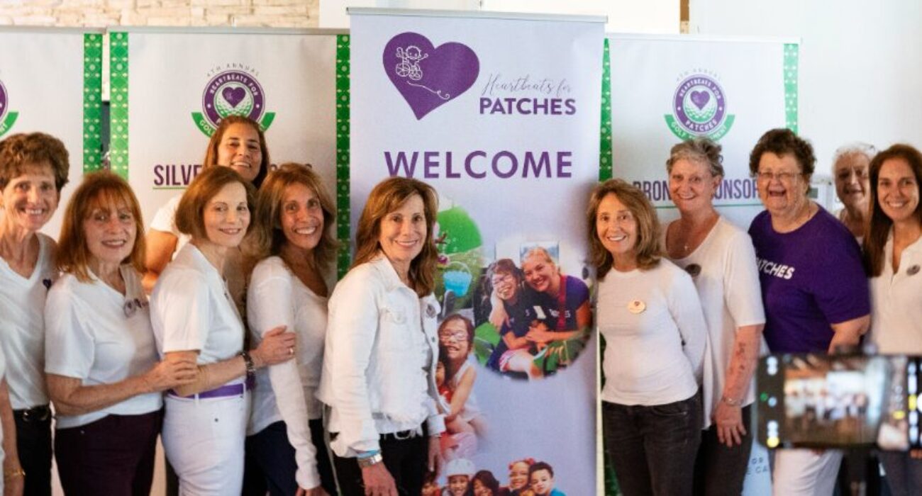 Group of women standing together in front of a welcome banner for a patch event.