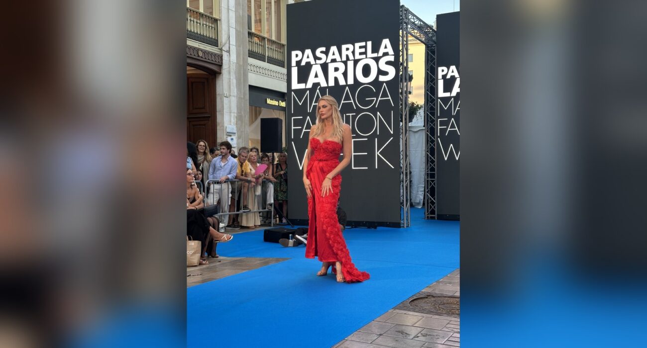 Model in a red gown in front of the Pasarela Larios Málaga Fashion Week sign