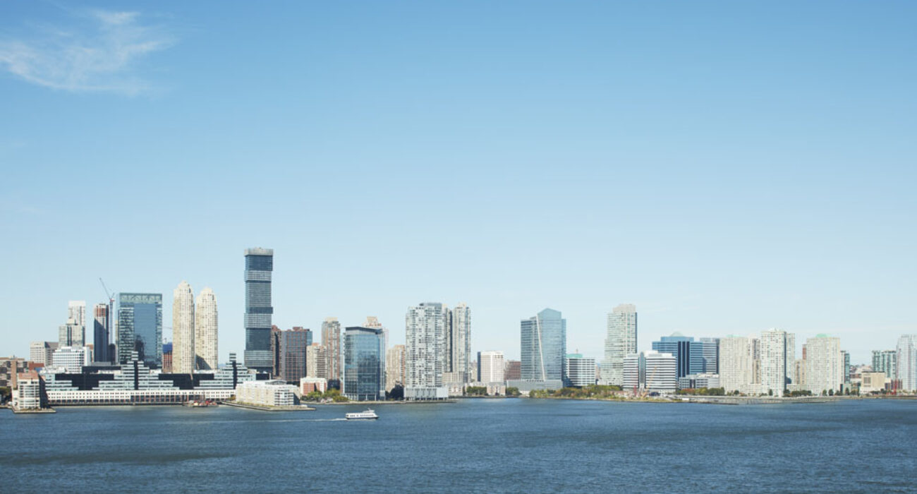 City skyline with buildings by the water under a clear blue sky.