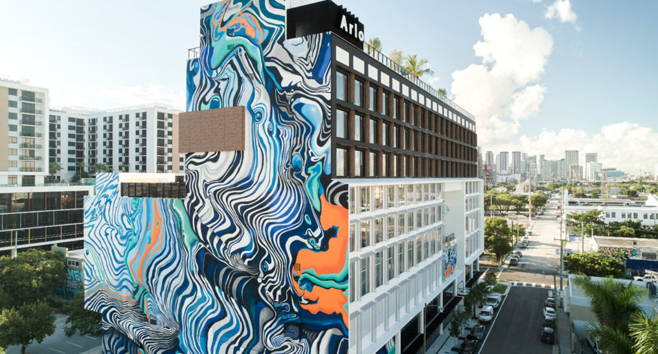 A tall building with vibrant blue and orange wave mural on its side.