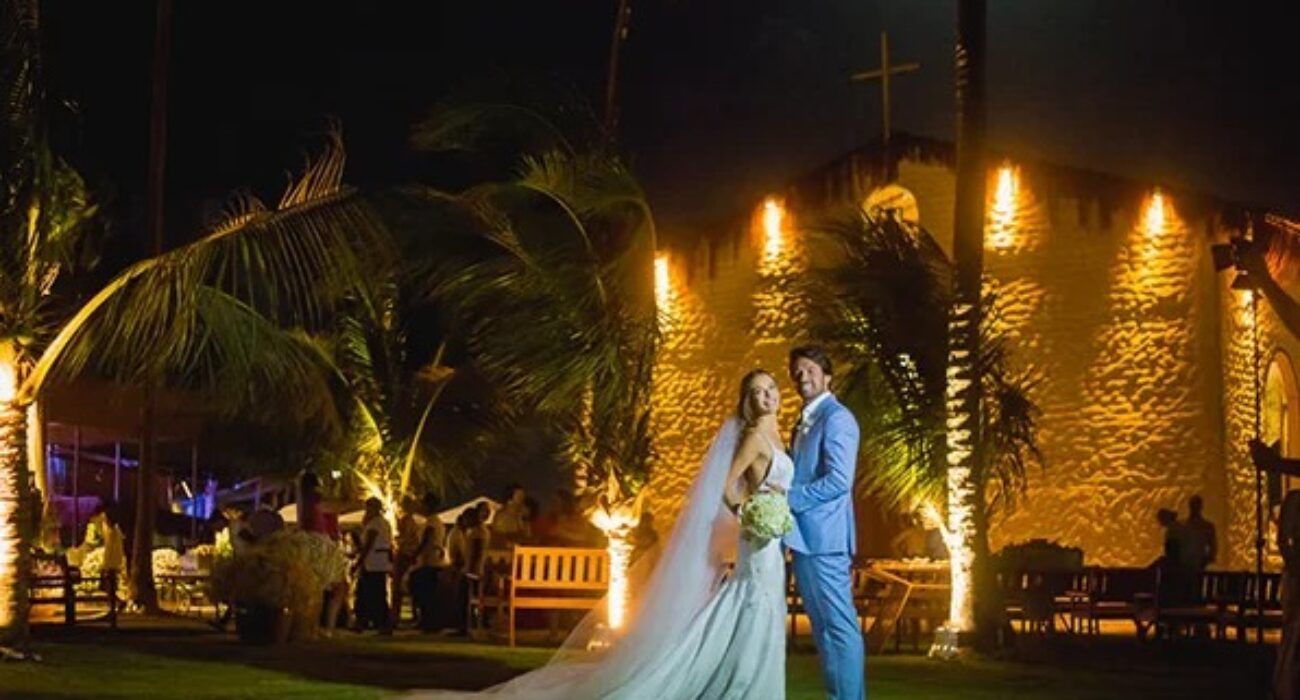 Newlyweds posing under glowing lights and crosses at night.