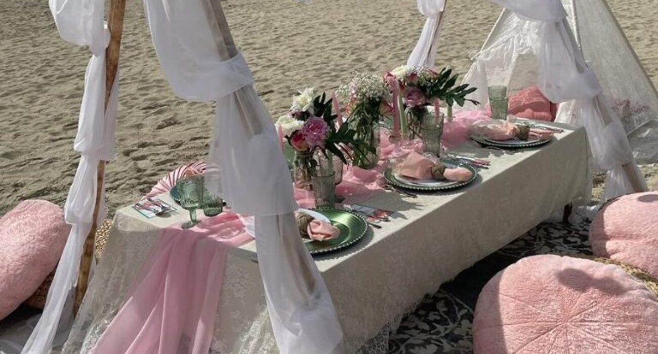 Elegant beachside table setup with pink and white decor for a special occasion.