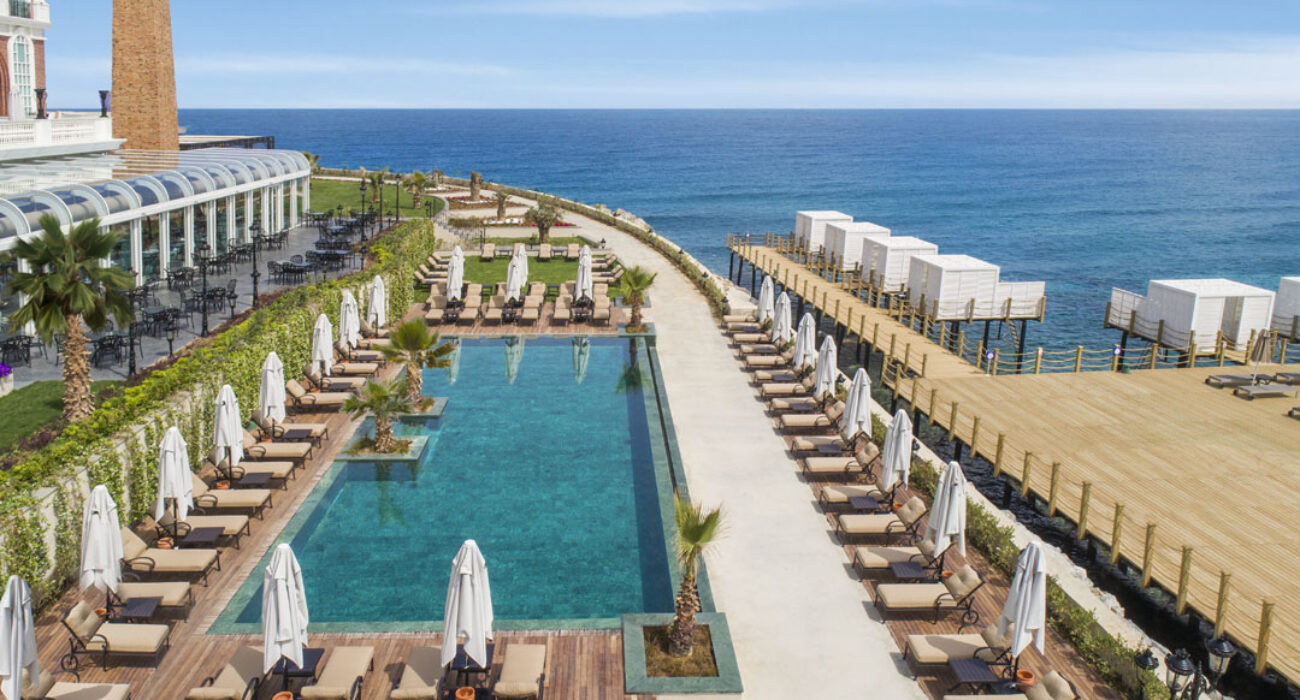 Elegant seaside resort pool with lounge chairs and cabanas.