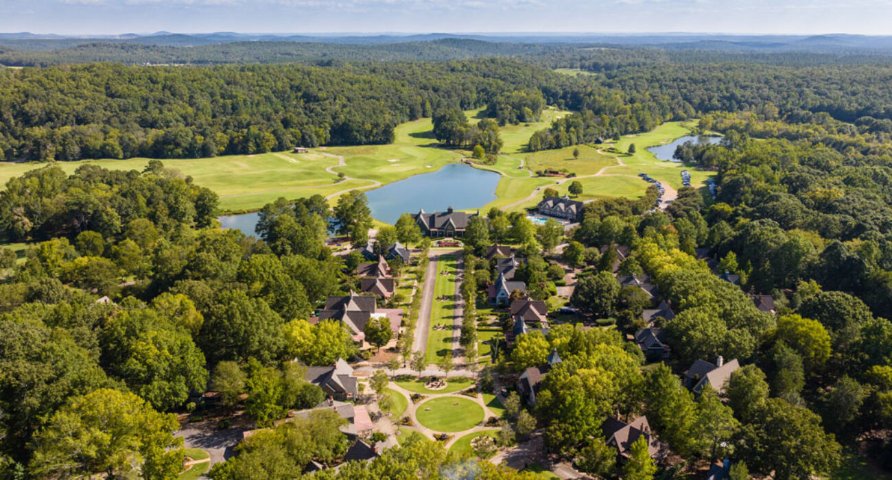 Aerial view of a scenic golf course surrounded by trees and houses.