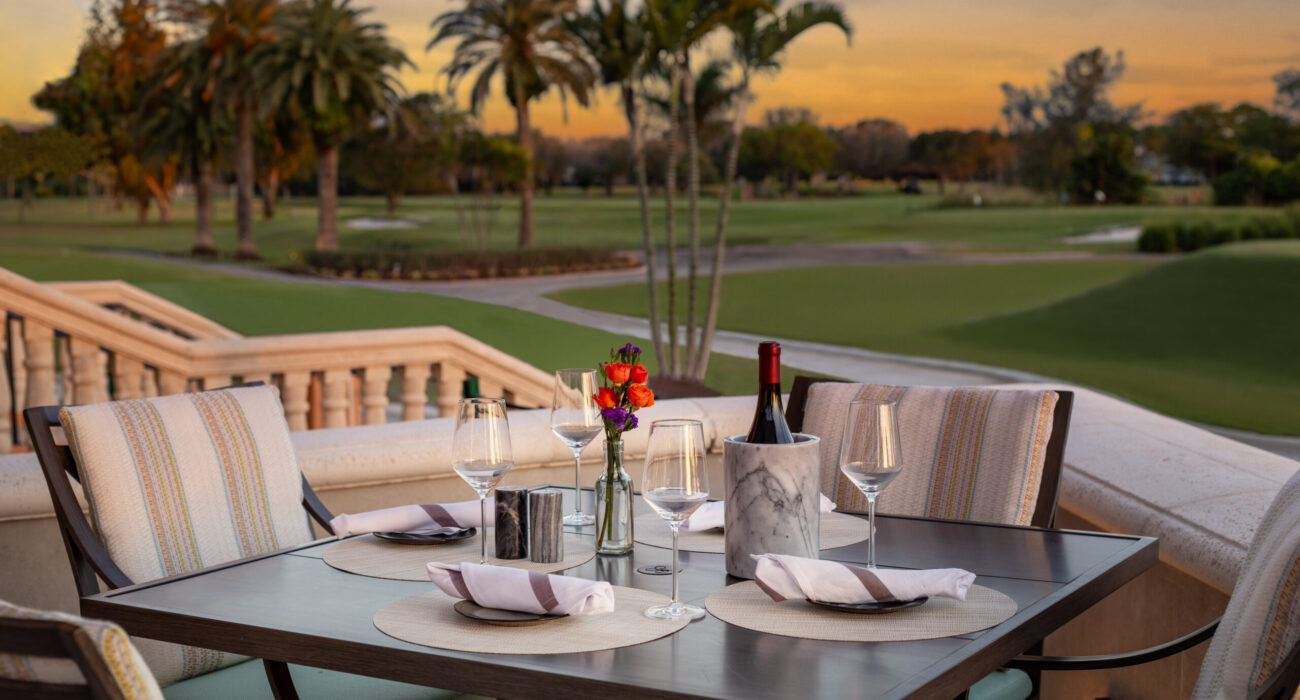 Elegant outdoor dining setup at sunset with a golf course view.