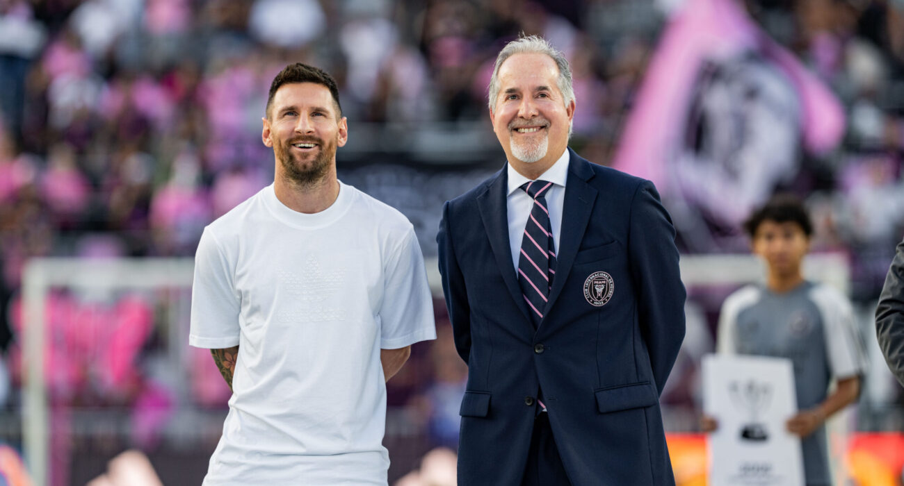 Lionel Messi standing beside a suited official at a stadium event.