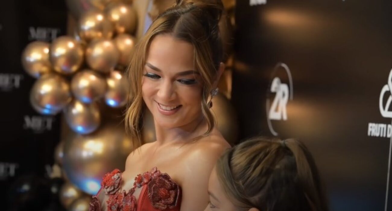 Woman in floral dress smiling at a child at a festive event.