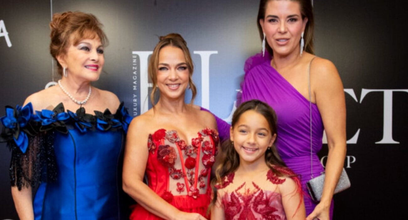 Four females dressed elegantly in vibrant evening gowns, smiling for a photo.