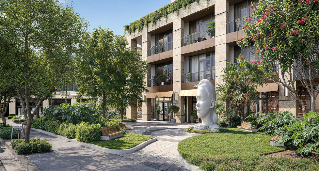 Modern building entrance with greenery, benches, and a large white face sculpture.