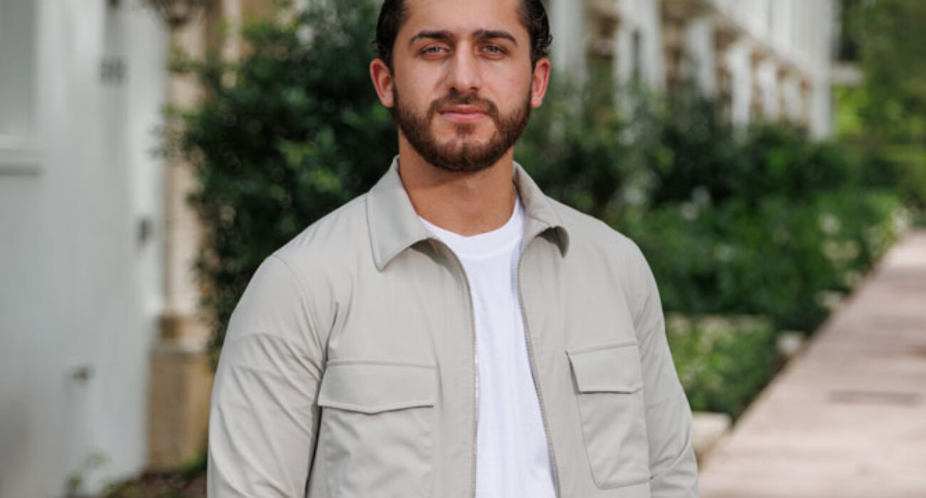 Man standing outdoors in a casual light jacket and white shirt.