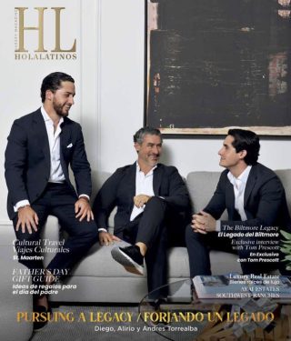Tres hombres de traje sentados y sonriendo en una moderna sala de estar de una oficina.