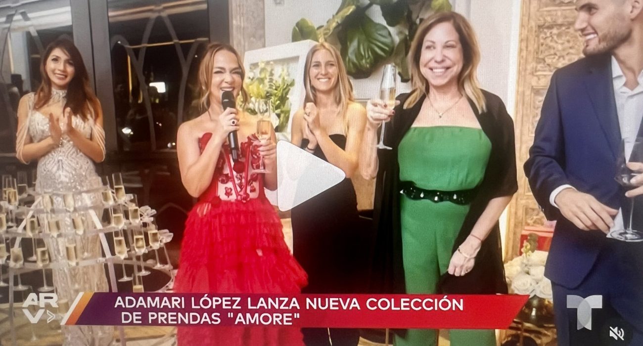 Three women smiling and toasting with drinks at a collection launch event.