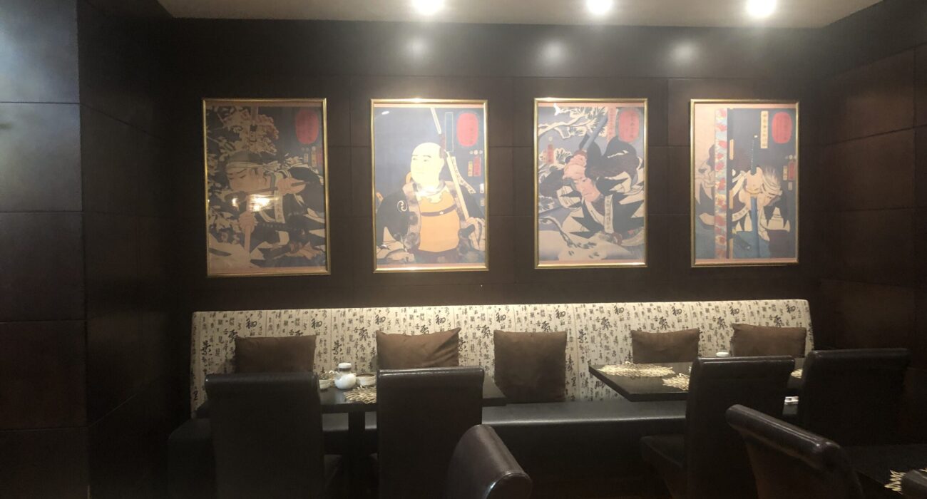 Cozy dining area with framed anime posters illuminated on the wall.