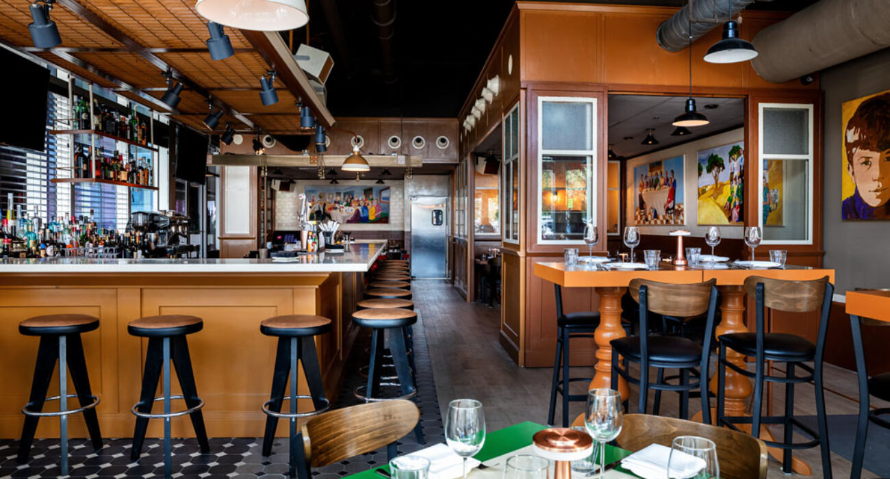 Cozy rustic restaurant interior with wooden stools and a green-set dining table.