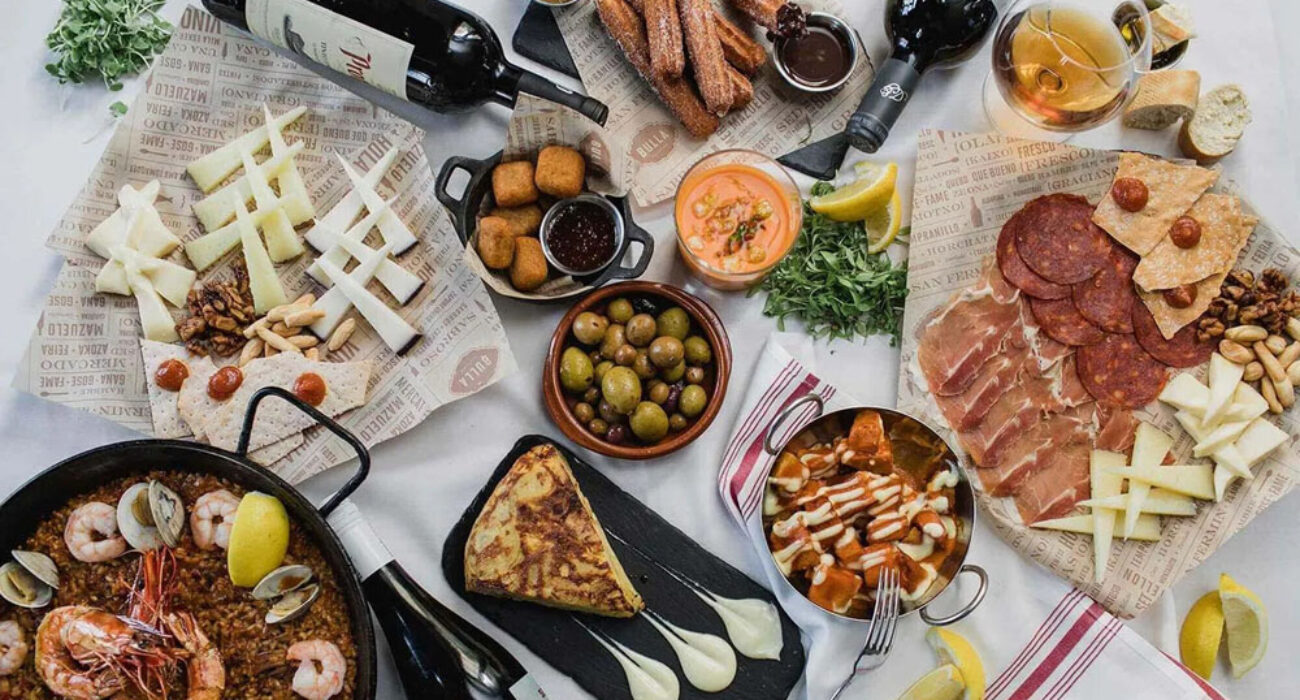 A vibrant spread of wine, cheese, olives, and charcuterie on a rustic table.