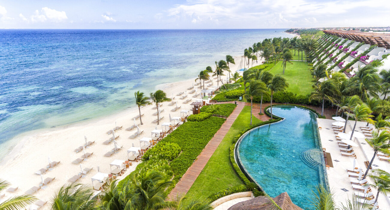 A tropical beach resort with palm trees and a curved pool.