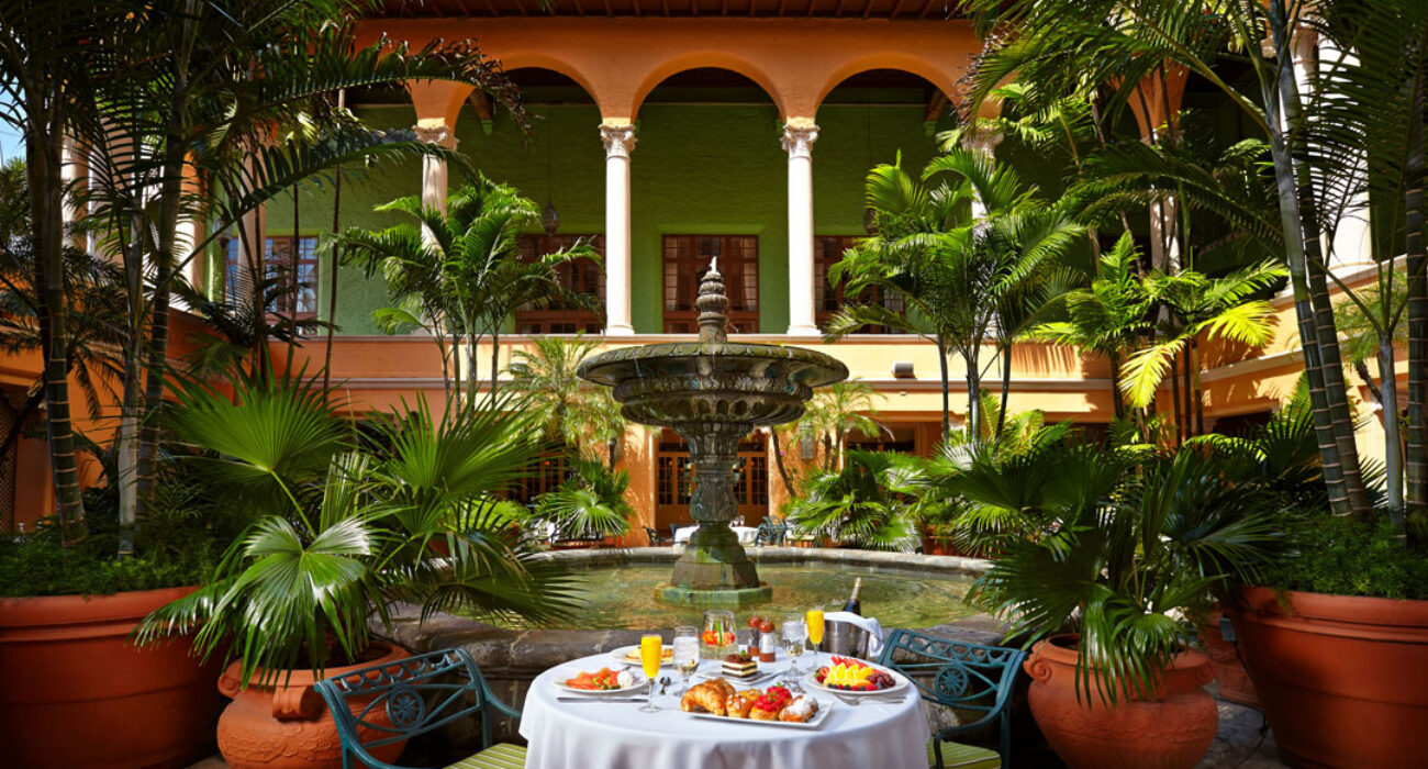 Elegant outdoor dining setup in a lush garden courtyard with tropical plants.