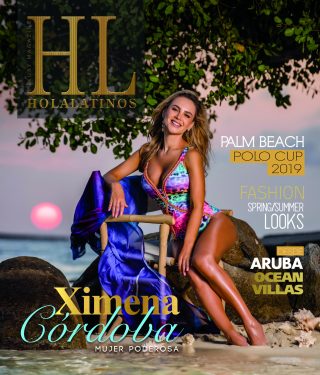 Una mujer en un bikini colorido posa sobre la estatua de un caballo azul al aire libre.