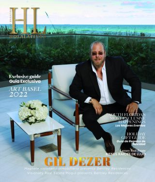 Gil Dezer posa junto al mar con un elegante traje negro, promocionando un evento de 2024.